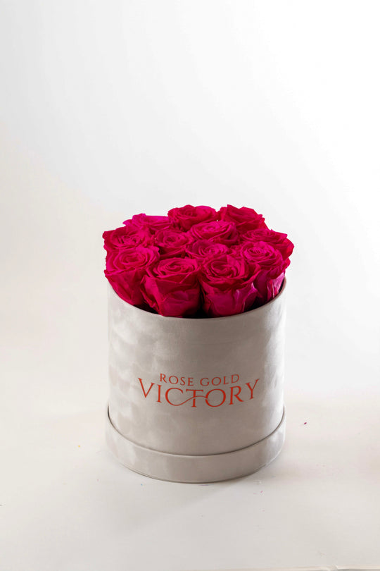 Hot pink preserved roses in a cream suede round keepsake box with the Rose Gold Victory logo