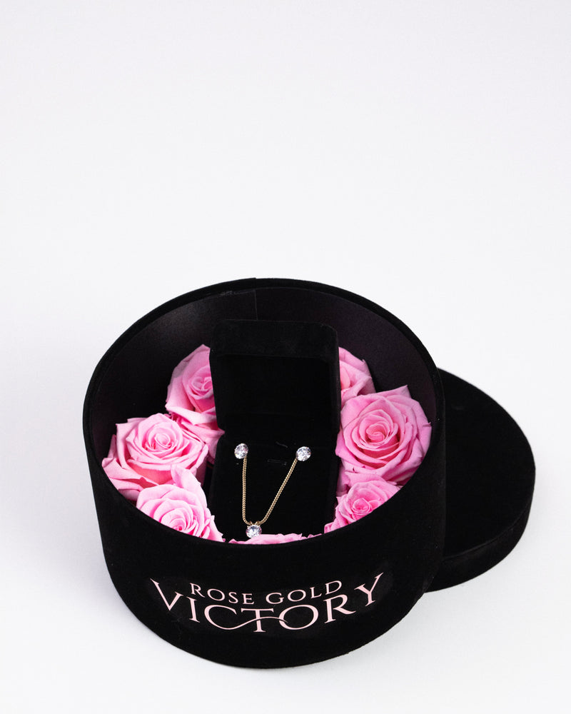 Pink preserved roses with a gold jewelry set in a black round box — Rose Gold Victory