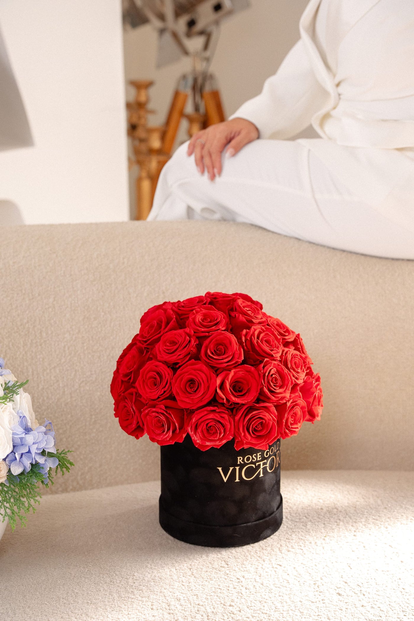 Rose Gold Victory red preserved-rose dome box styled on a curved cream sofa